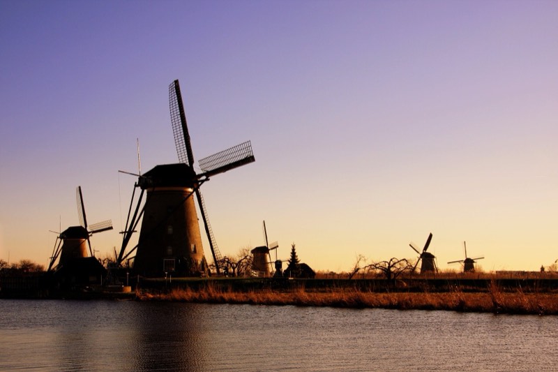 Windmills reflected in still water at Kinderdijk at sunset